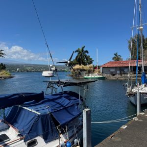 View of the blue waters of Hilo Bay with sailboats resting along a wharf and with Mauna Kea off in the distance