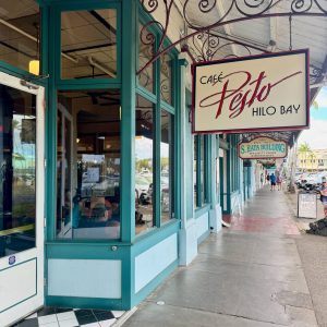Hilo Bayfront shops with the Cafe Pesto Hilo Bay sign and glassfilled walls with light green trim and a clean polished cement walkway