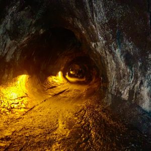 Thurston Lava tube at Kilauea Volcano with floor lighting splashed giving a haunted level and orange view of the floor off into the distance